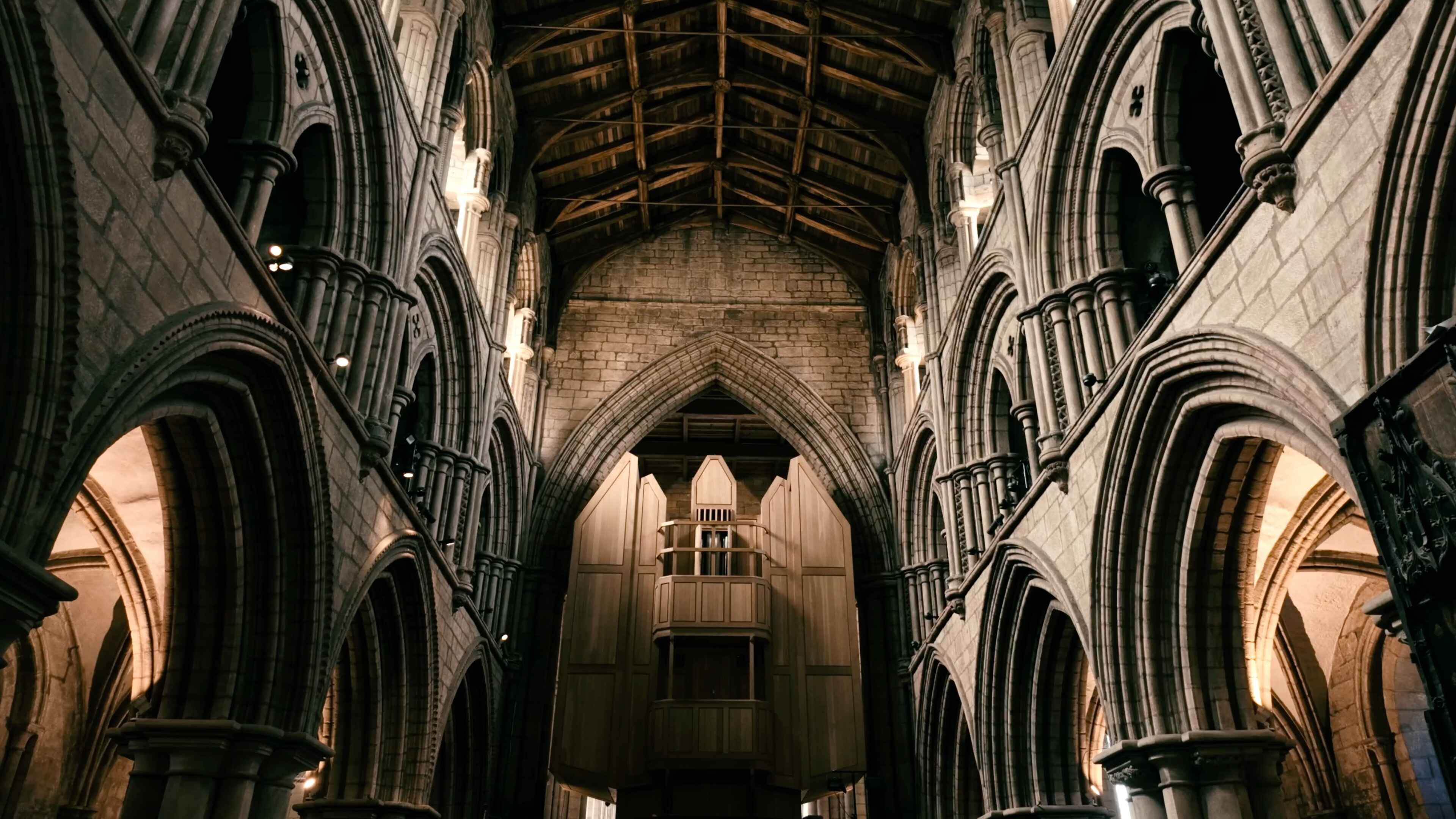 A large organ in the centre of an elegant cathedral with a wooden-slatted roof