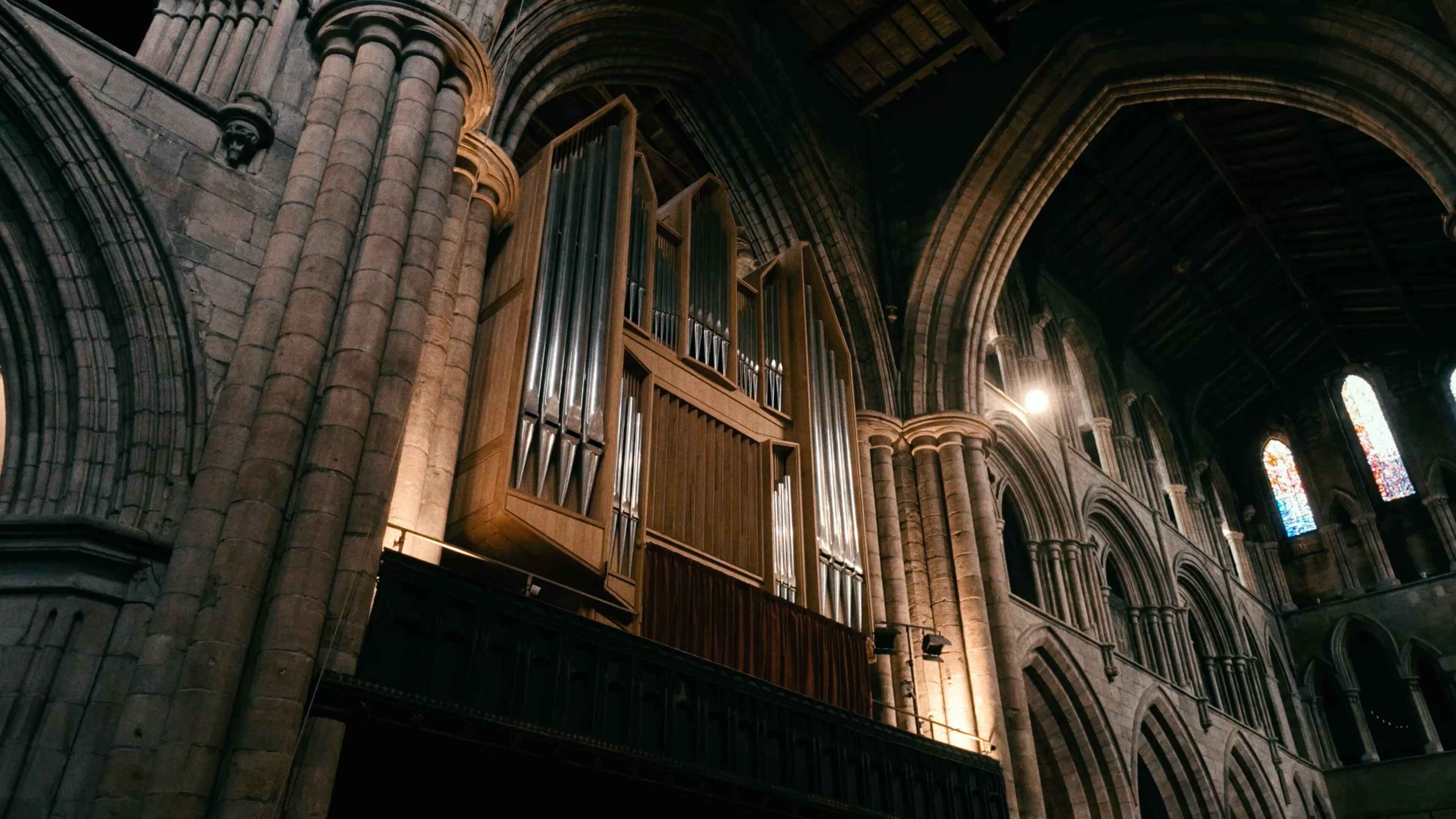 A grand organ mounted to the stone walls of a large abbey