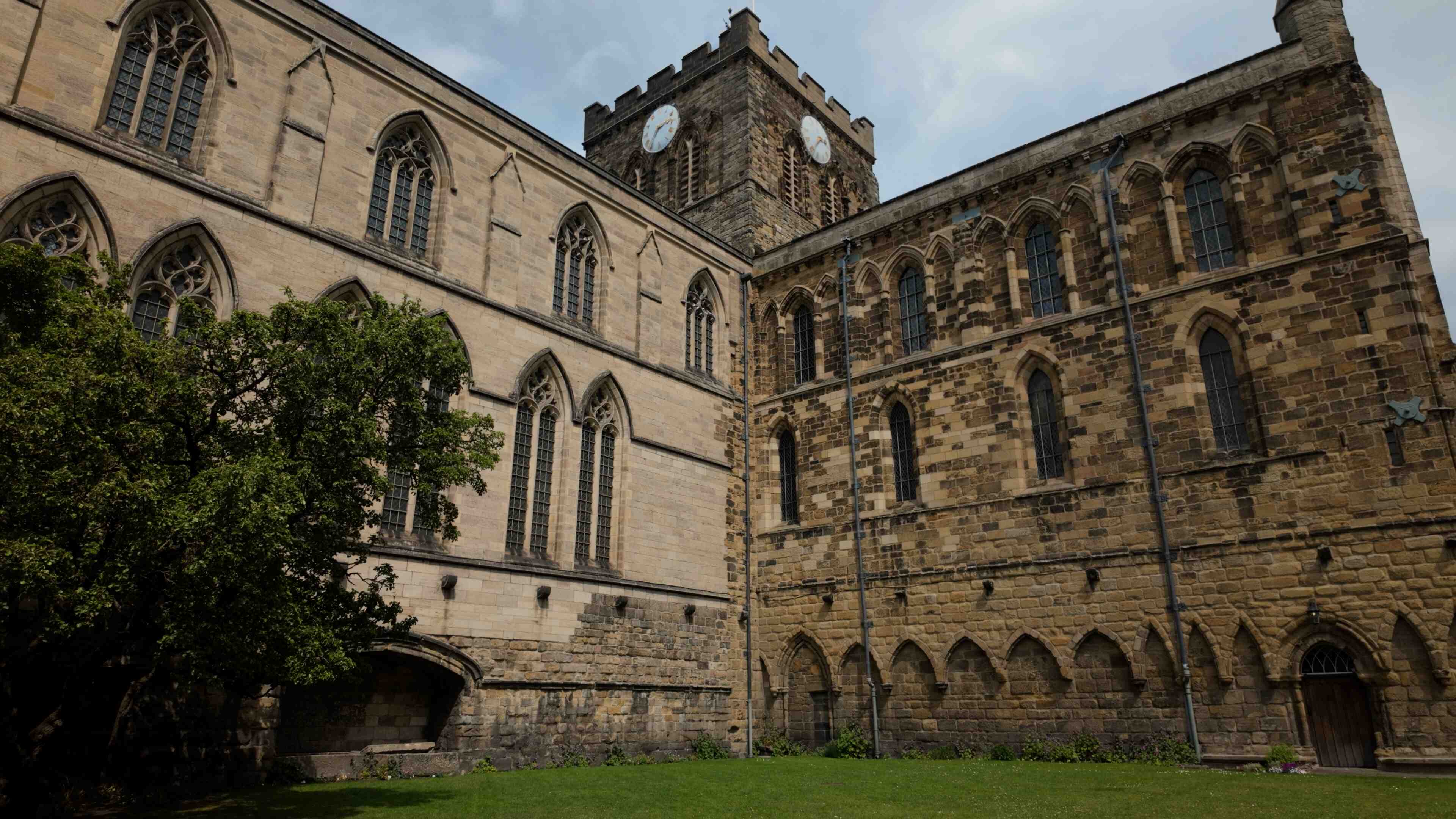 A large historic church against a cloudy blue sky and trees to the left
