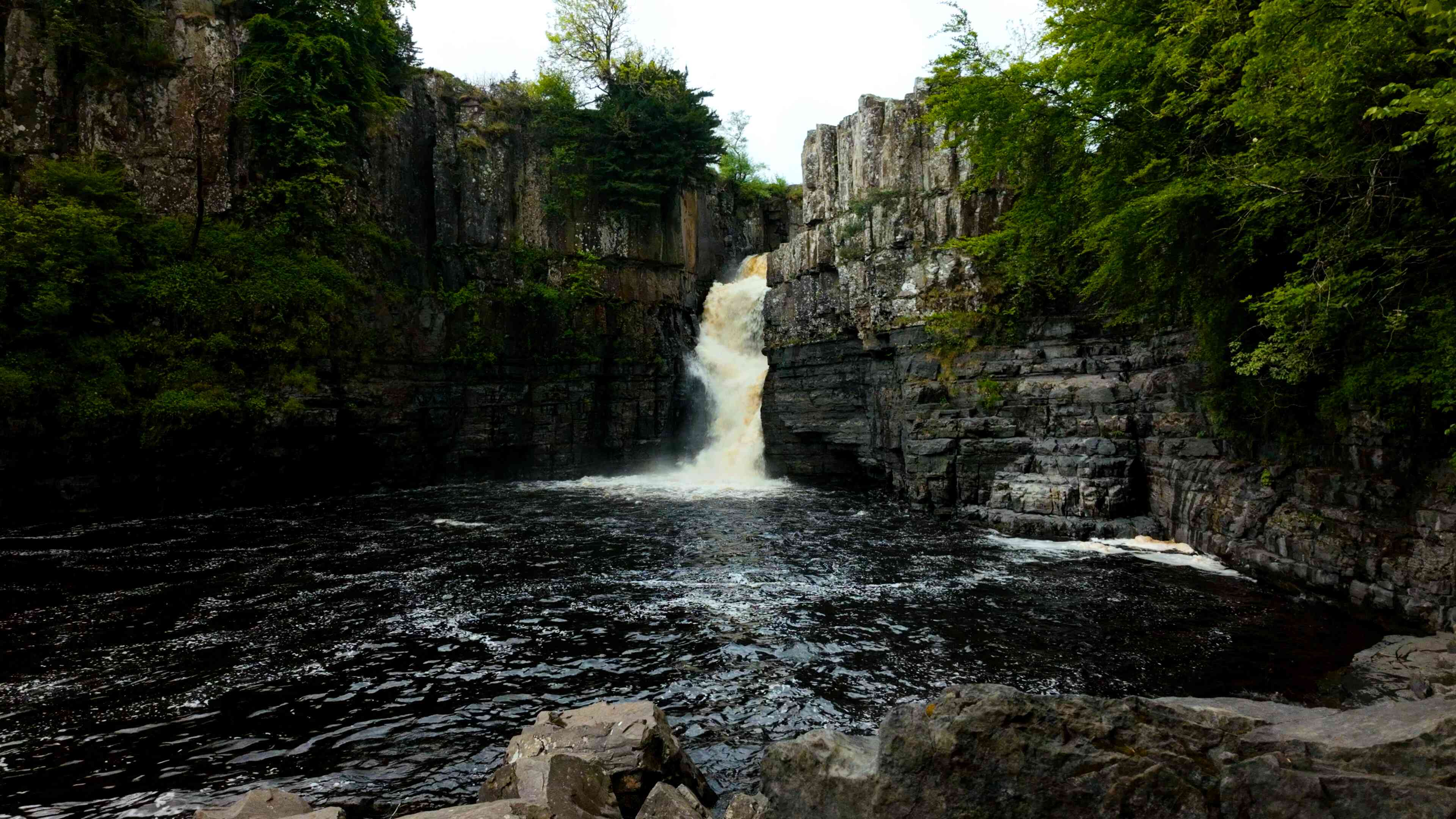 A large, towering waterfall surrounded by cliffside
