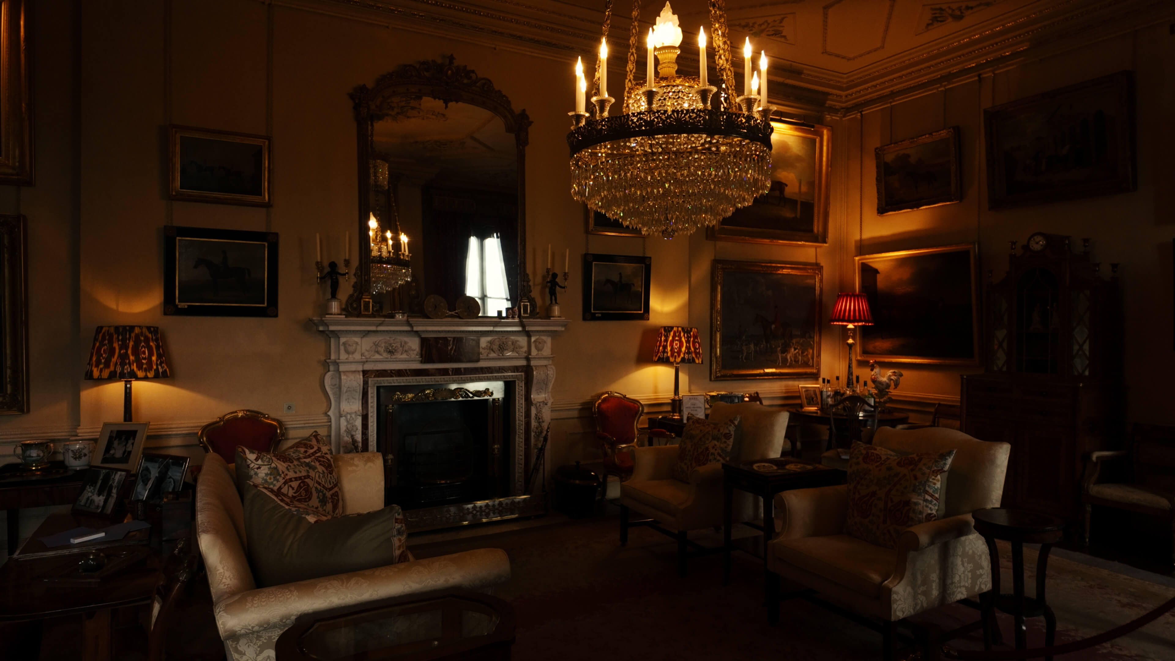 A warmly decorated room with a fireplace, comfortable chairs, and a decorative chandelier illuminating the space