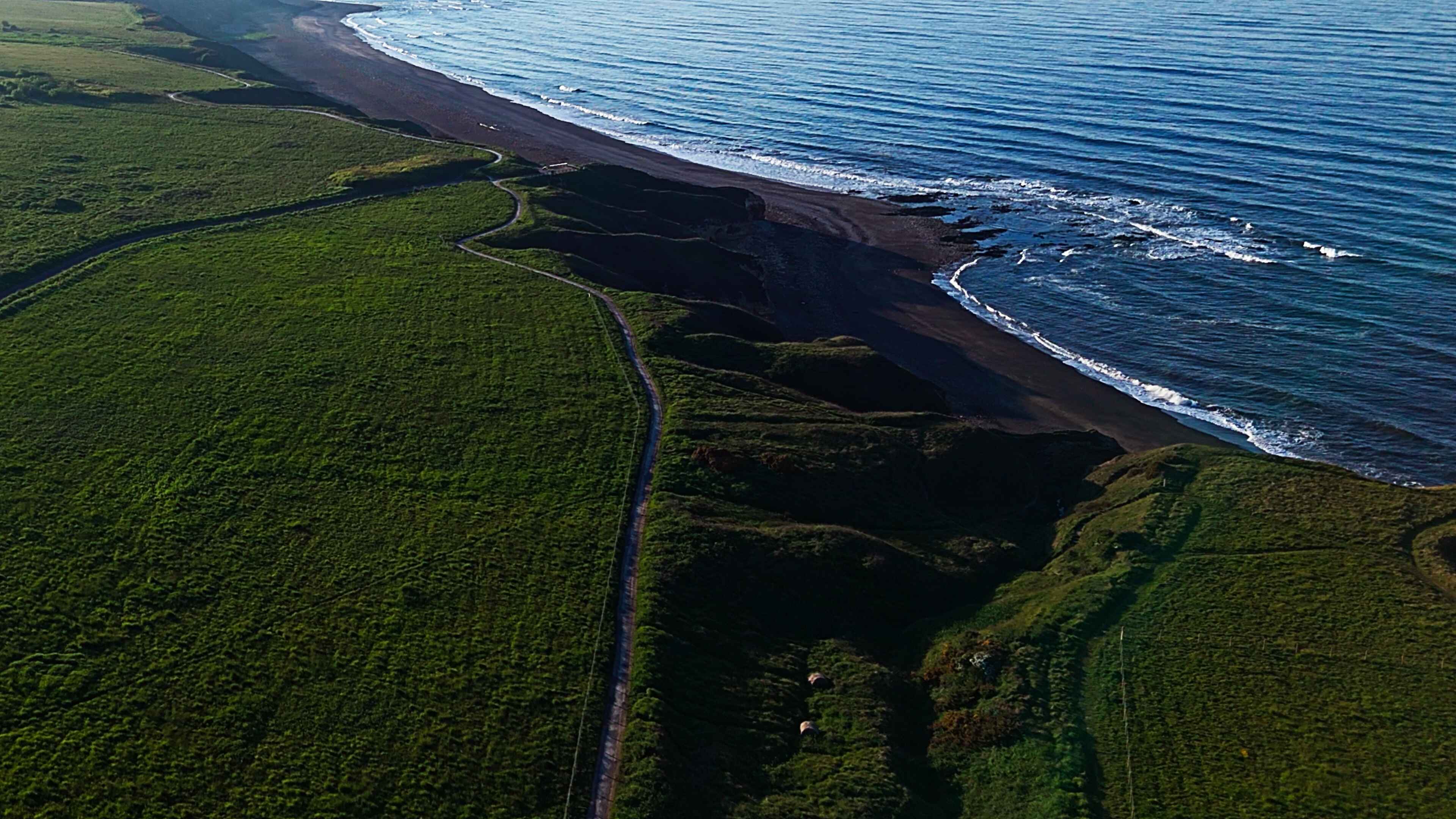 Lush green cliffs to the left and striking blue waters on the right