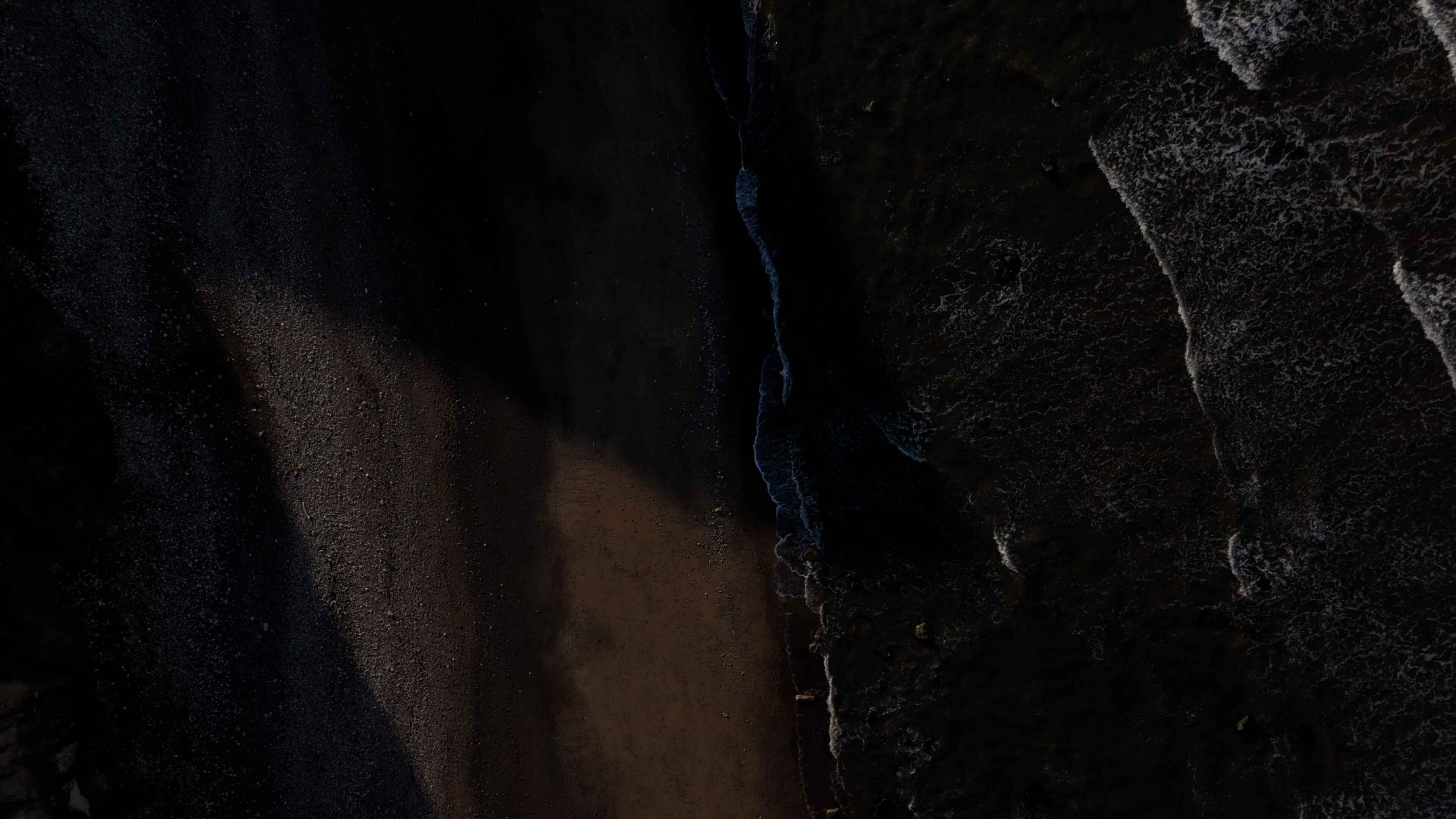 Water overlaps black-tinted sand along a shoreline
