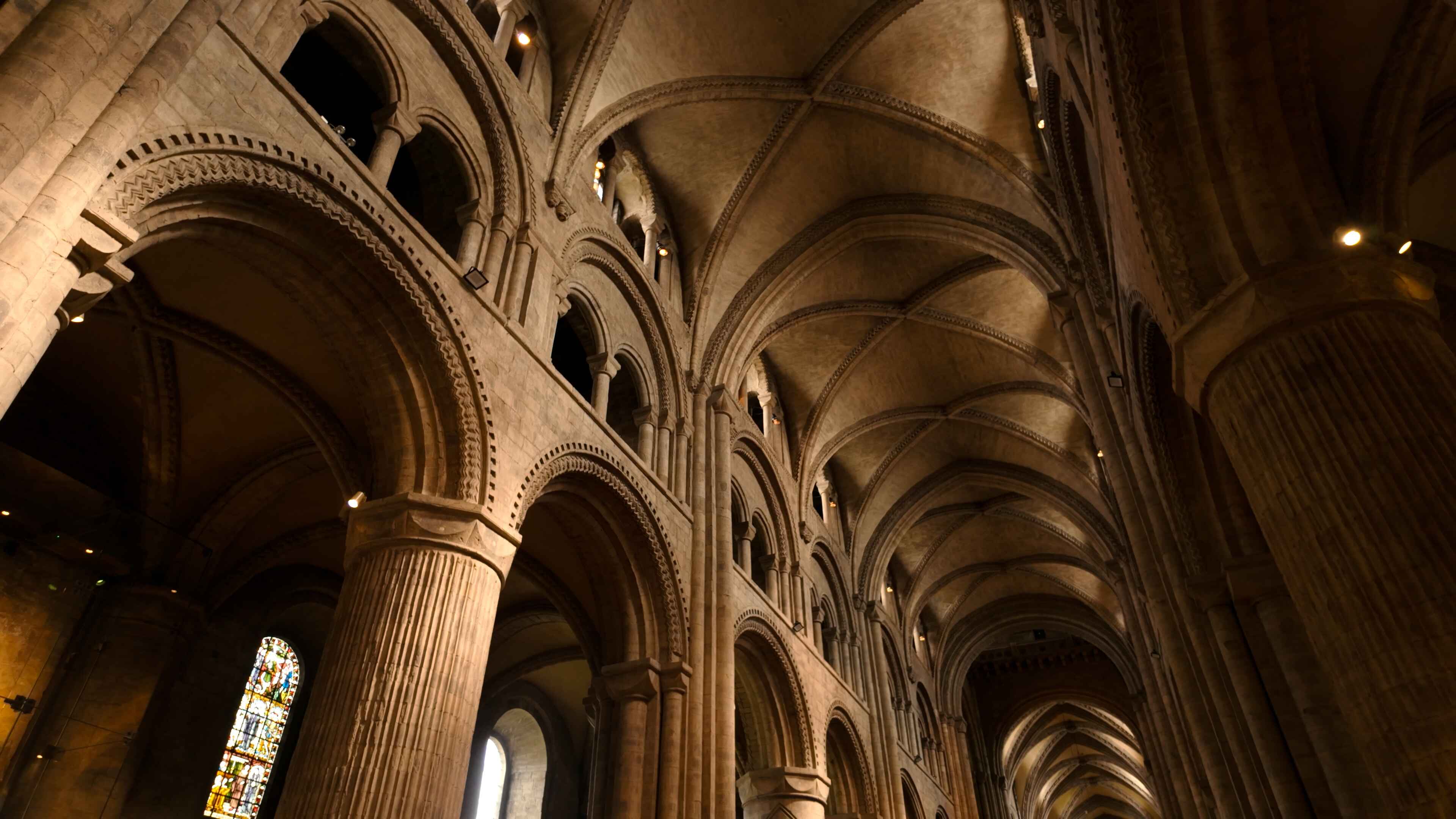 Interior view of a cathedral featuring tall arches and stained glass windows illuminating the space