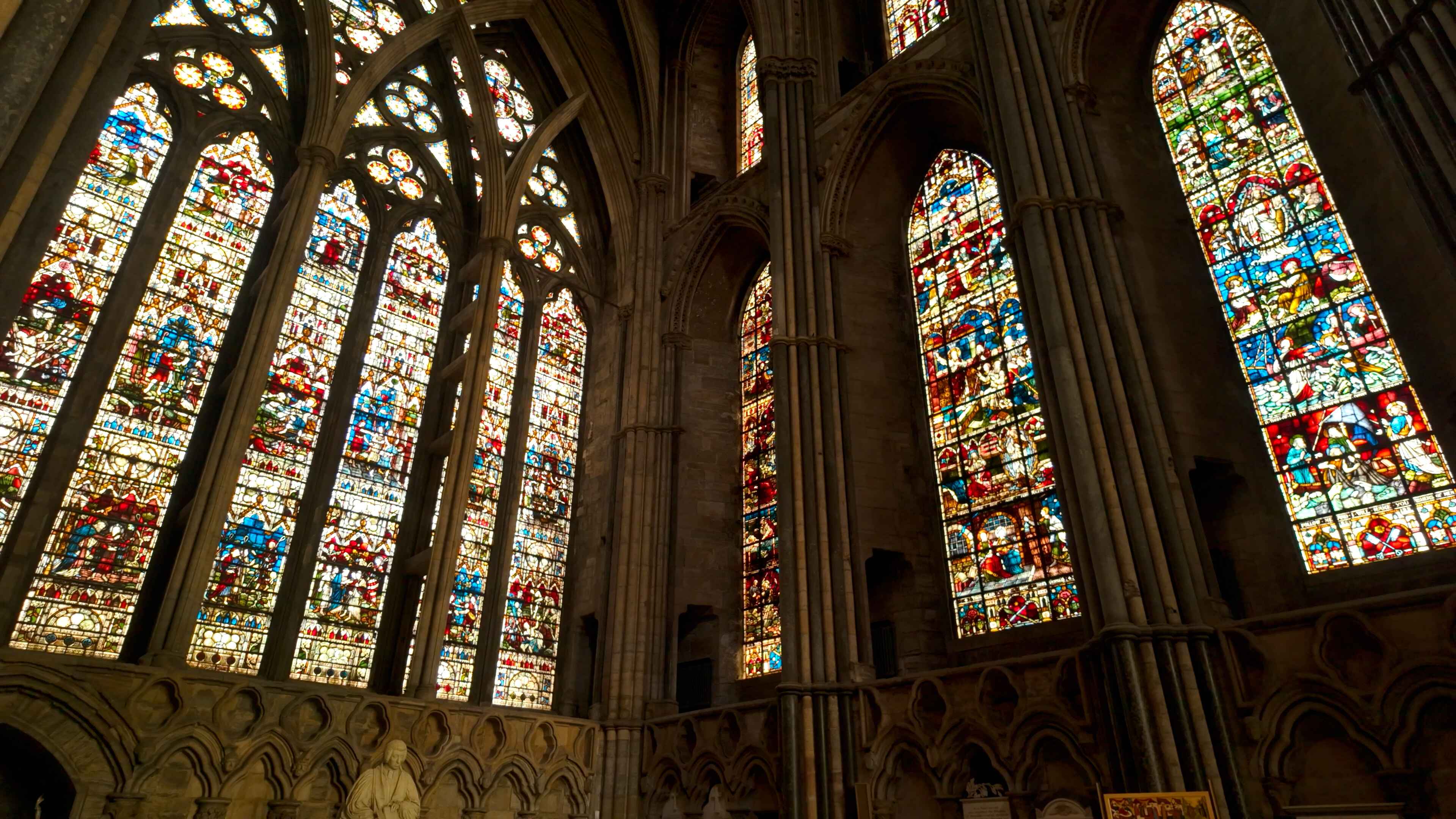 A large cathedral featuring intricate stained glass windows and a statue underneath