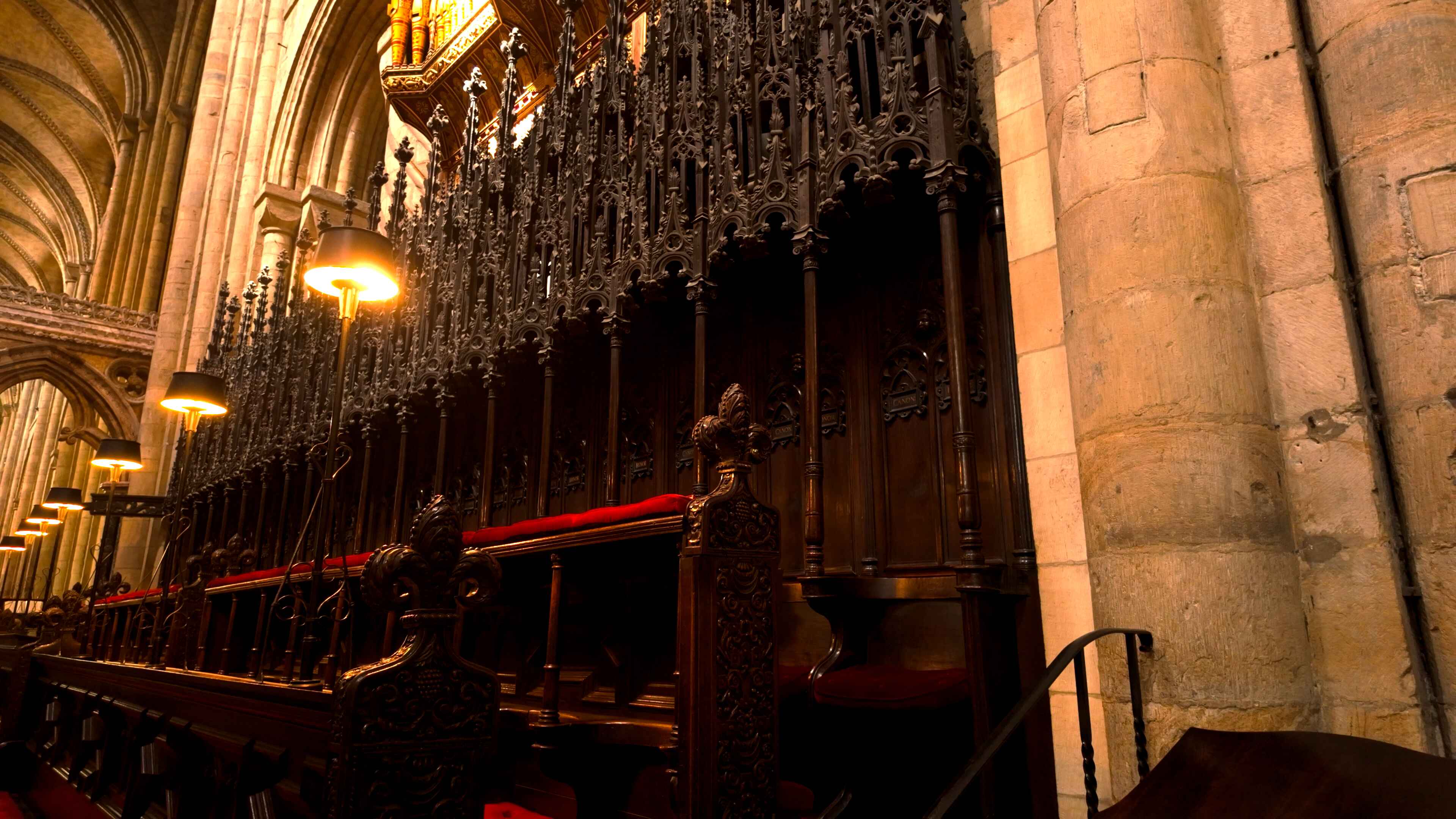 Choir pews lined with red velvet seats and a series of lights above