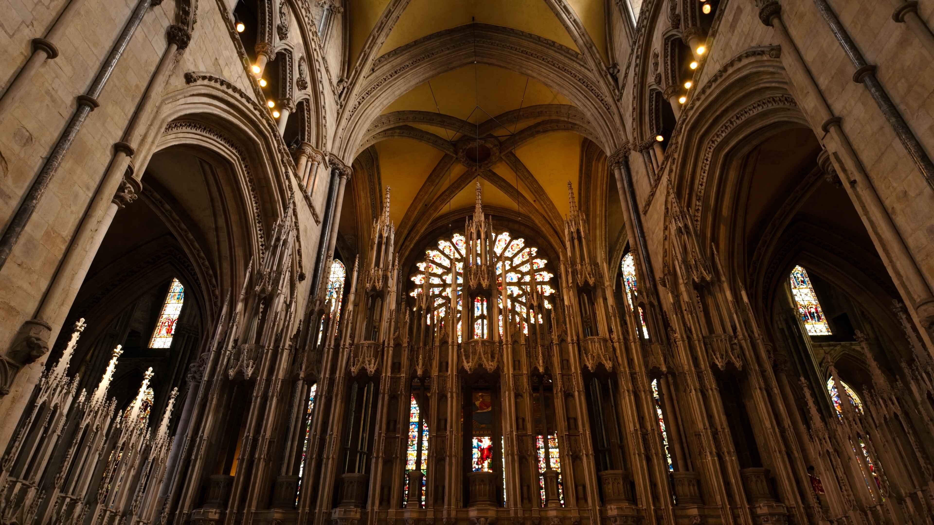 Grand, intricately designed cathedral archways and spires with stained glass windows behind