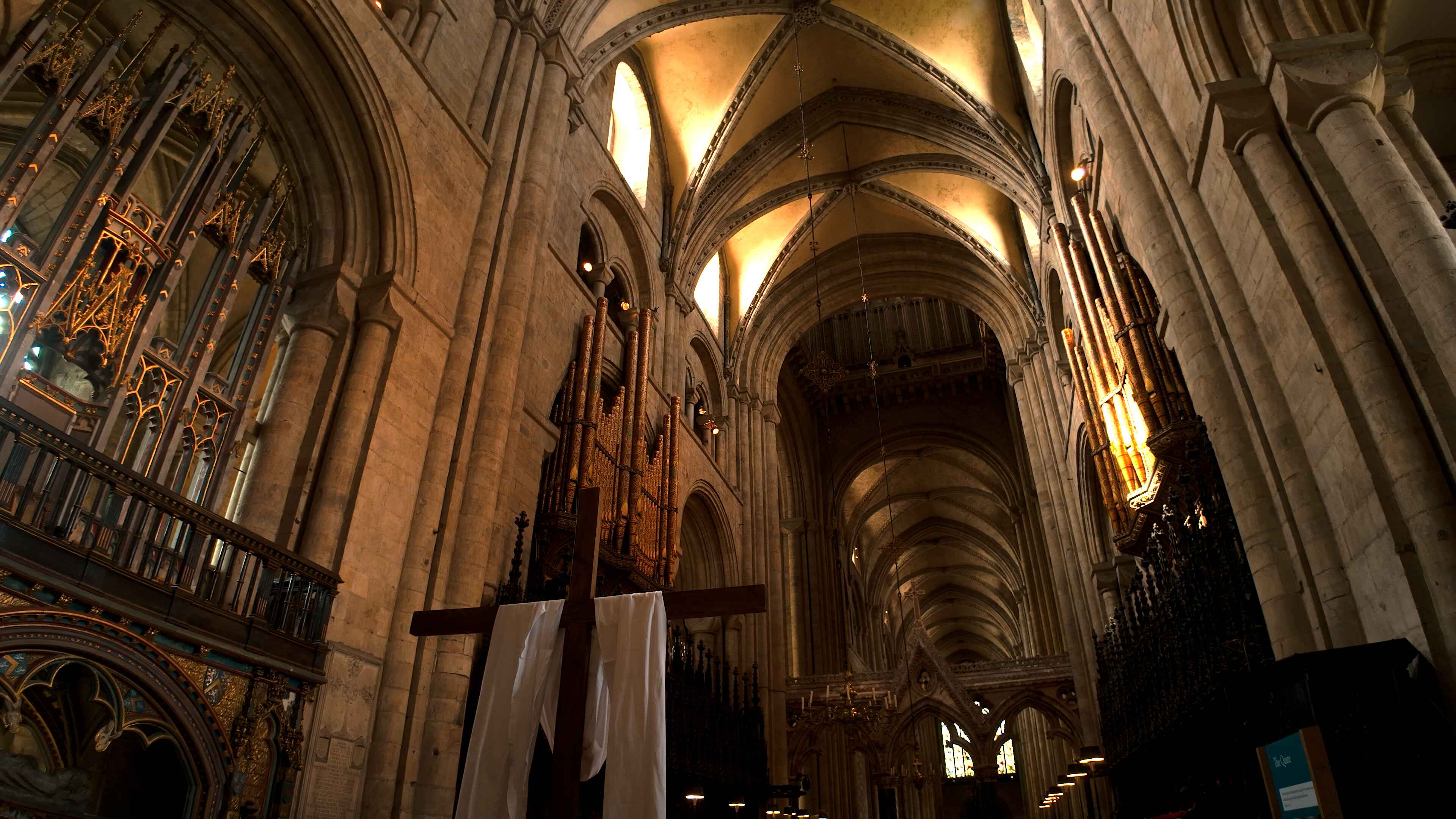 A large cathedral interior featuring a prominent cross and organ pipes mounted on a wall