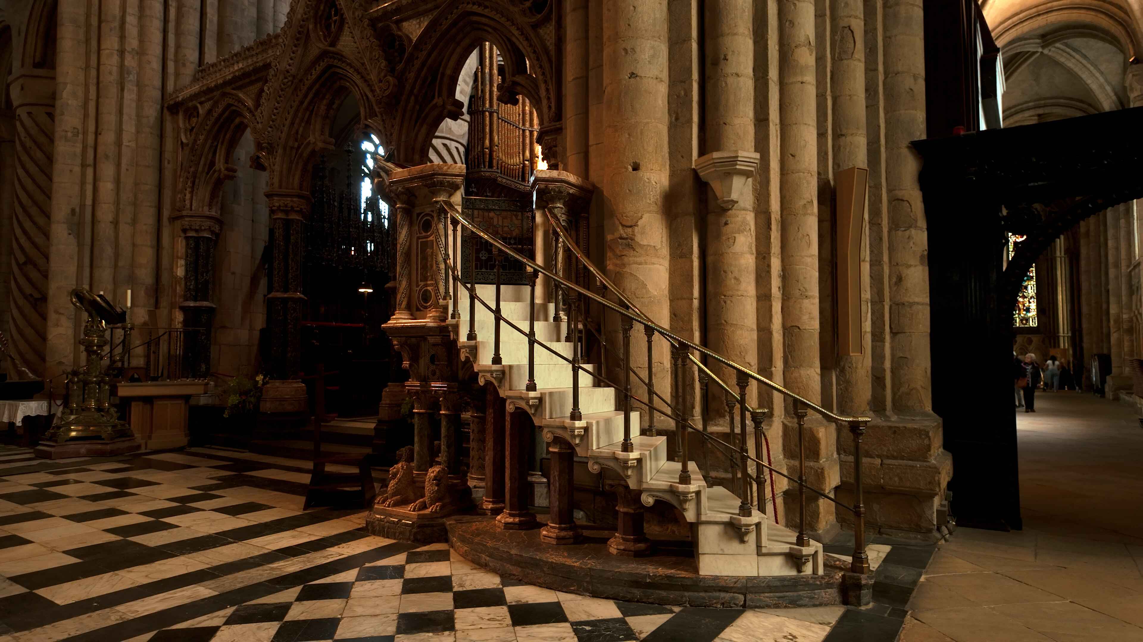 Intricately designed staircase curling around a pillar with granite flooring