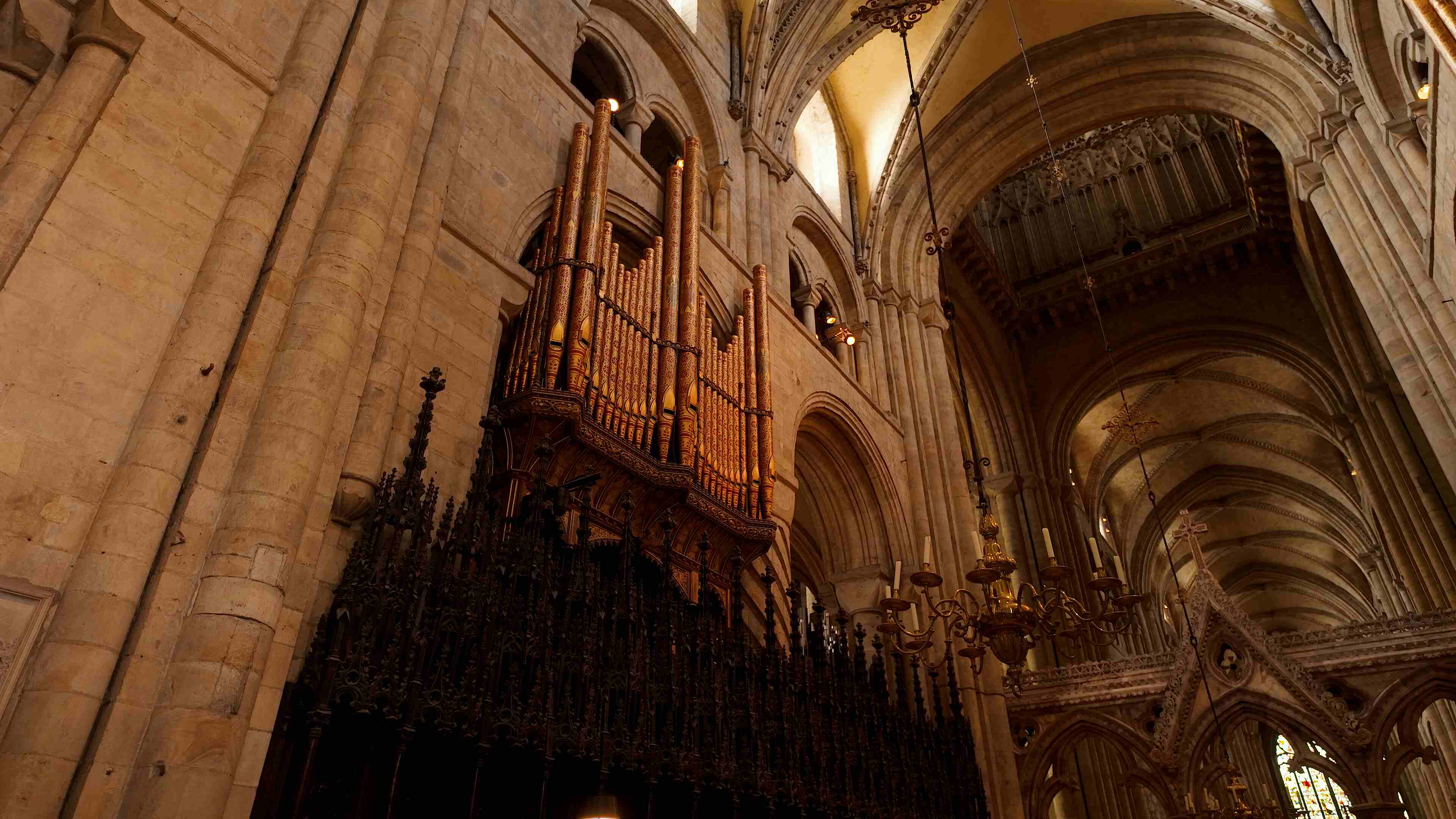 A grand organ inside Durham Cathedral, showcasing intricate pipes and ornate design against a historic backdrop